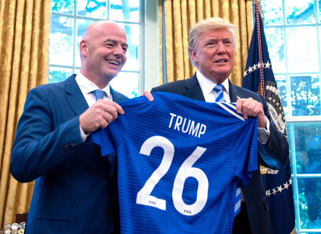 US President Donald Trump and FIFA President Gianni Infantino at the White House in 2018, celebrating the 2026 World Cup, which will take place in the USA as well as Canada and Mexico. They are stood next to each other and holding up a football shirt which has 'Trump 26' on the back of it. Credit: Action Plus Sports Images 